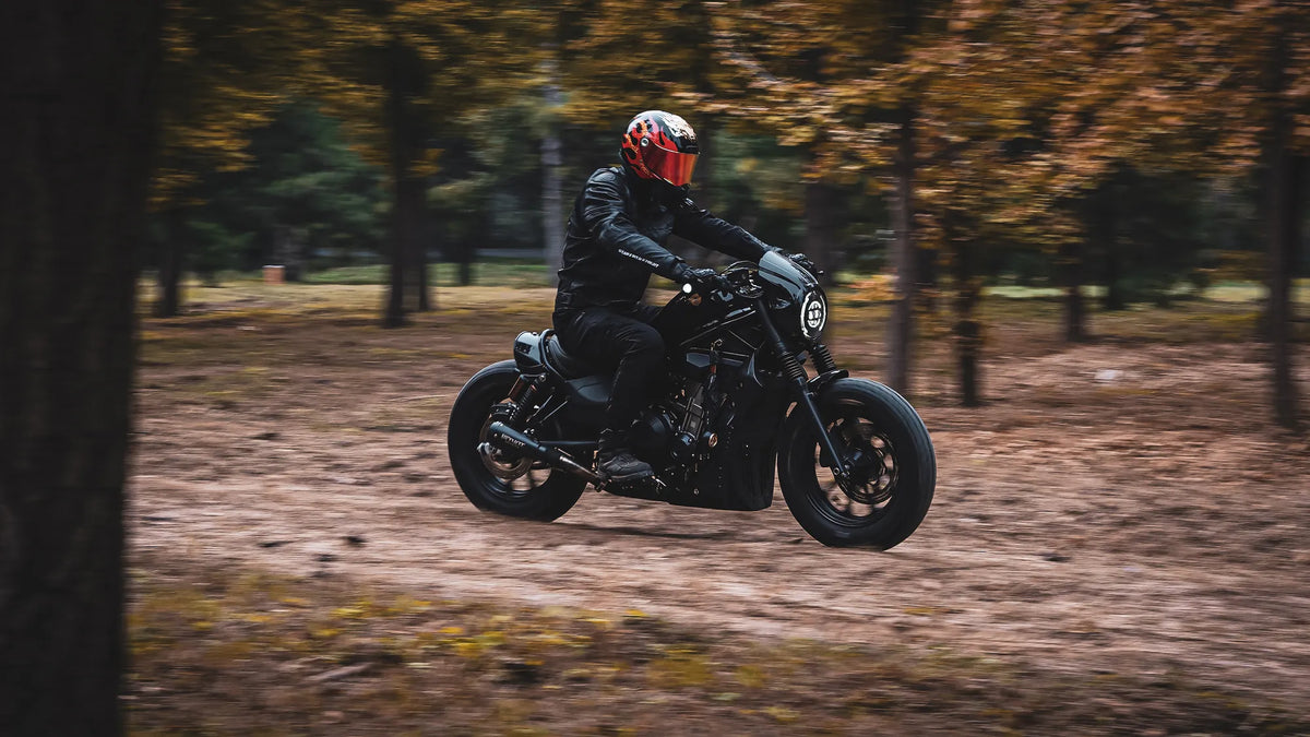 Rider in a full-face helmet riding a cruiser through a wooded path