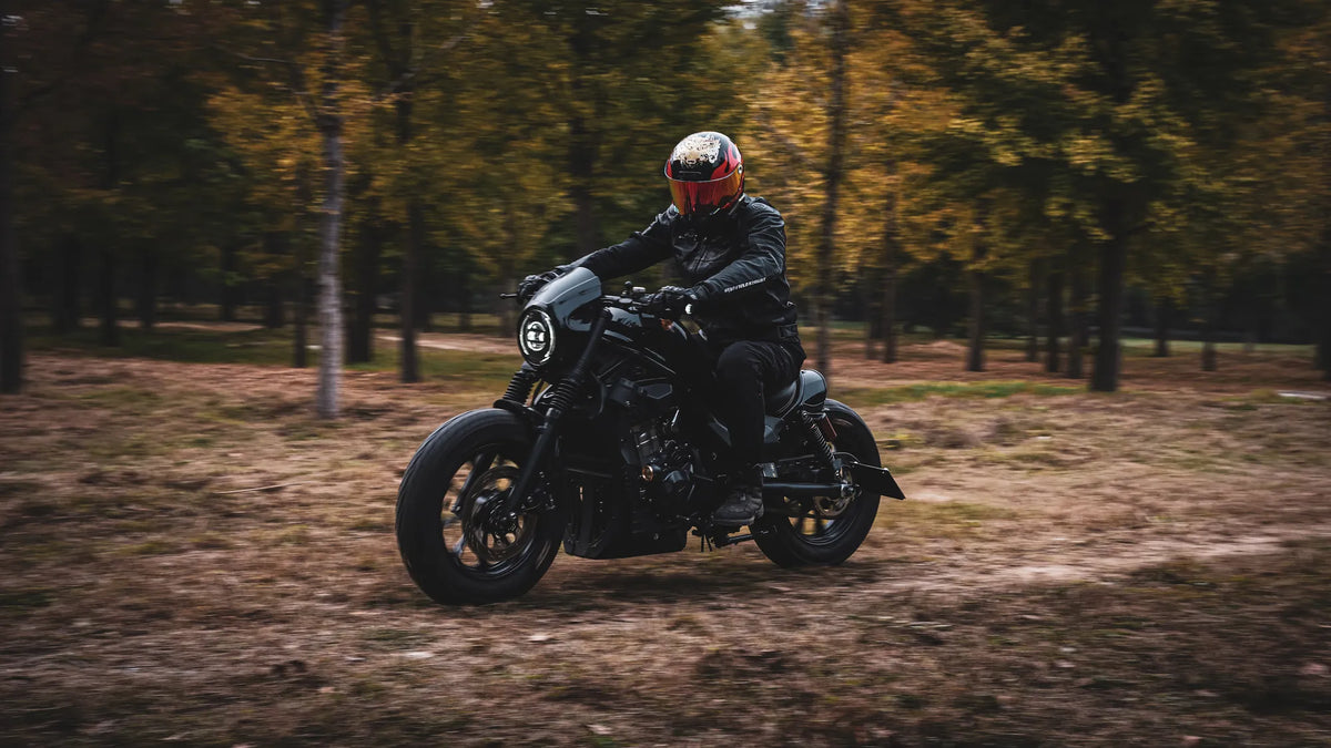 Rider in a red full-face helmet on a cruiser in an autumn forest