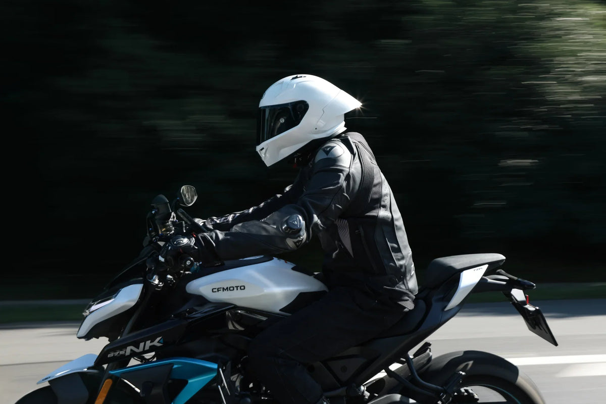 Rider in a white full-face helmet on a naked bike, motion blur background