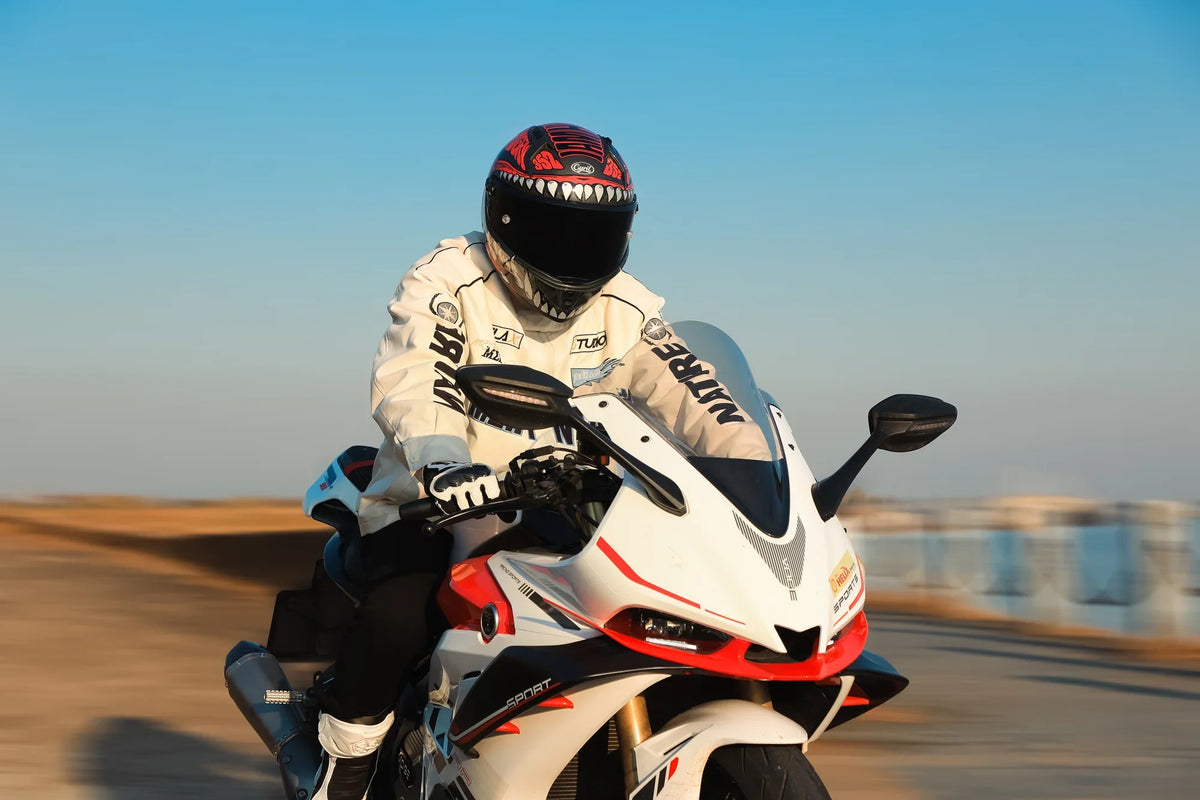 Rider in a full-face helmet and white jacket on a sport bike at sunset