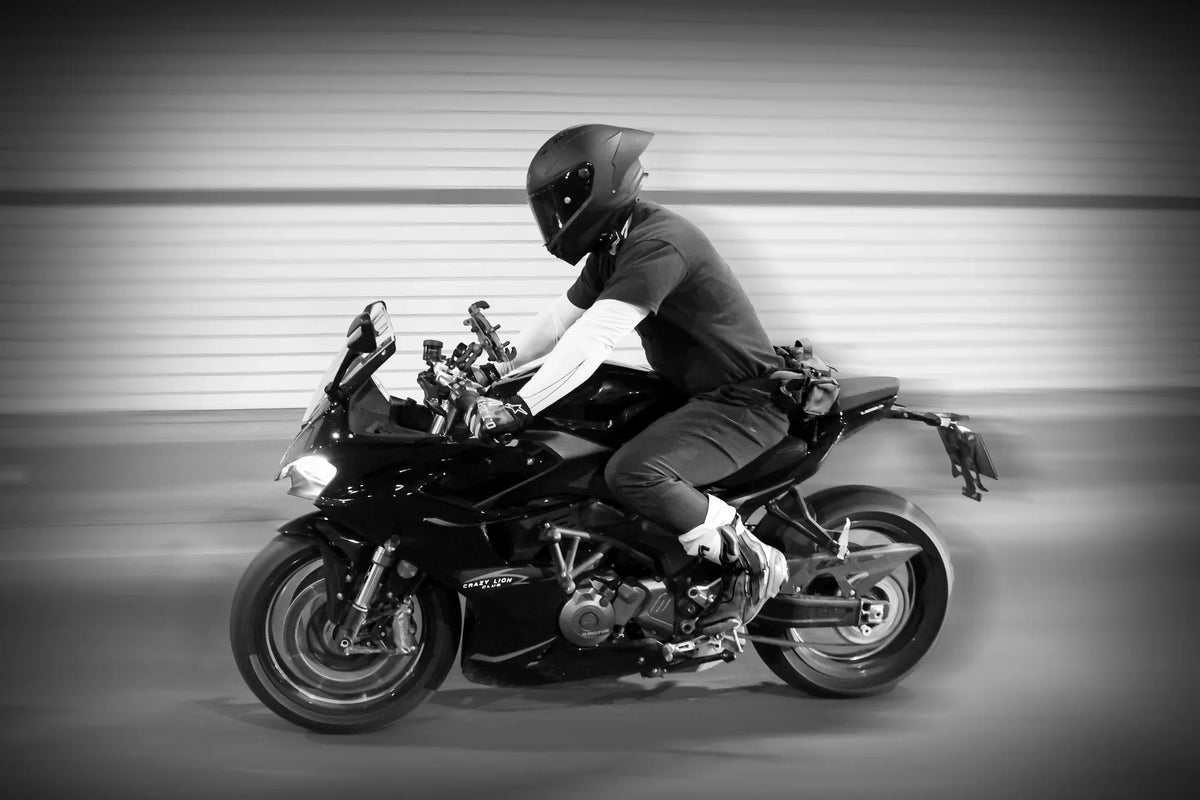 Rider in a full-face helmet on a sport bike, black and white motion shot
