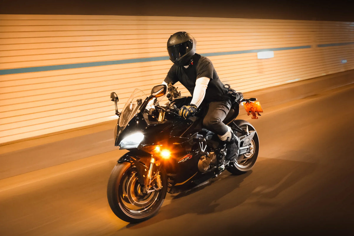 Rider in a black full-face helmet on a sport touring bike under warm light