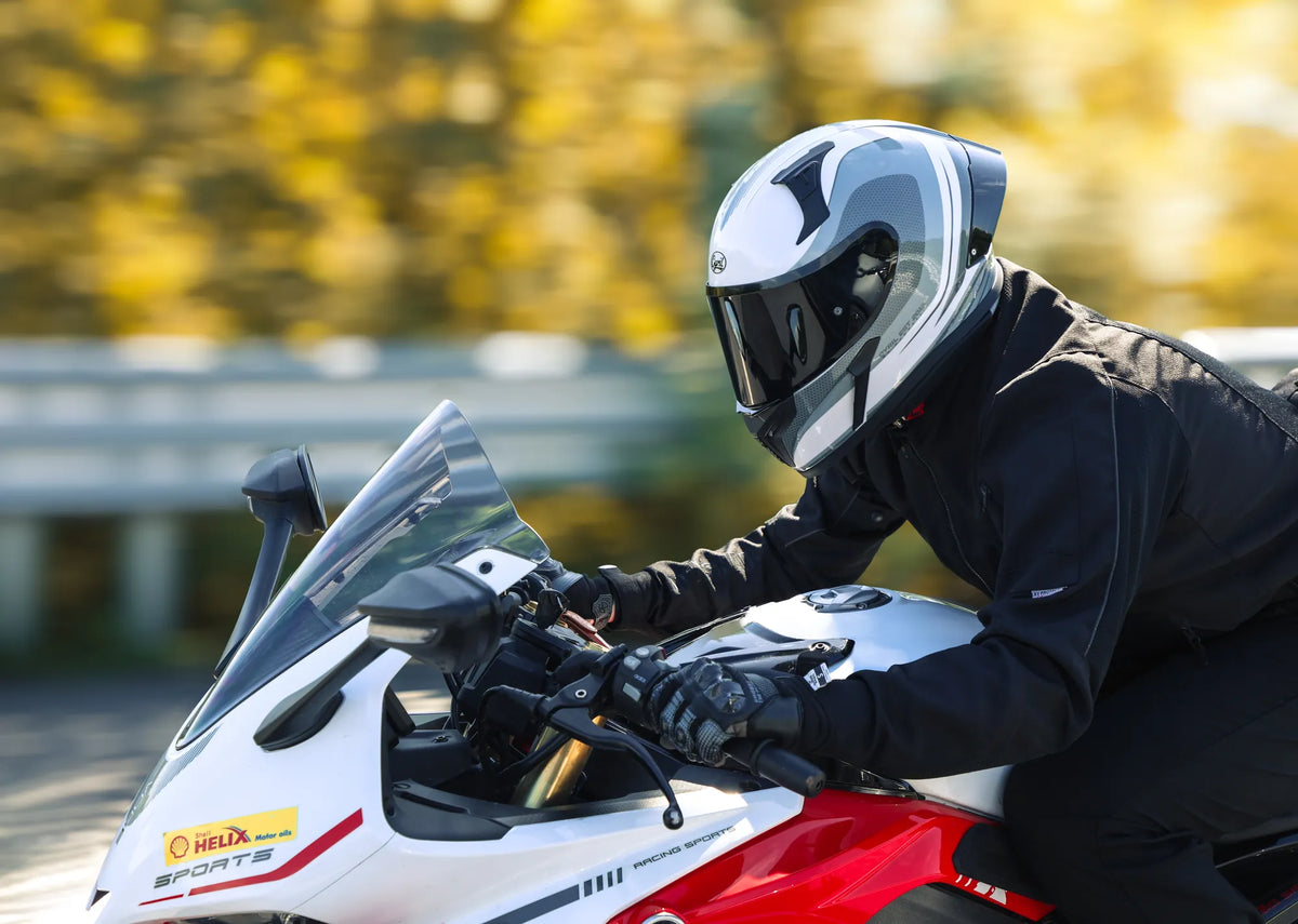 Rider in a white and gray full-face helmet on a white sport bike