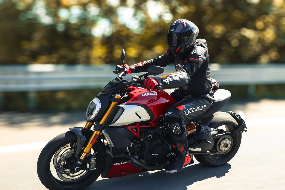Rider in a full-face helmet on a red cruiser in sunlight