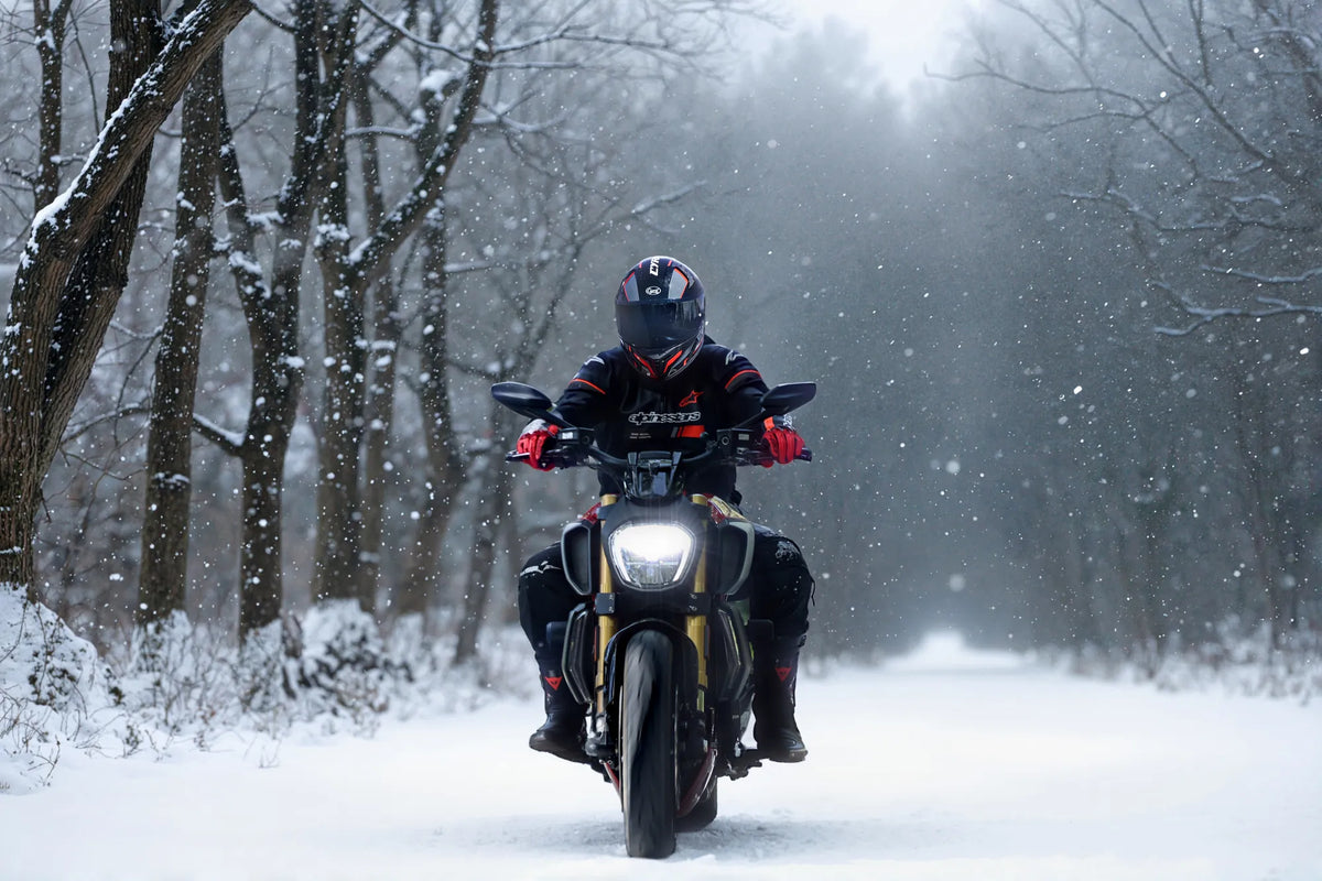 Rider in a full-face helmet on a motorcycle in falling snow
