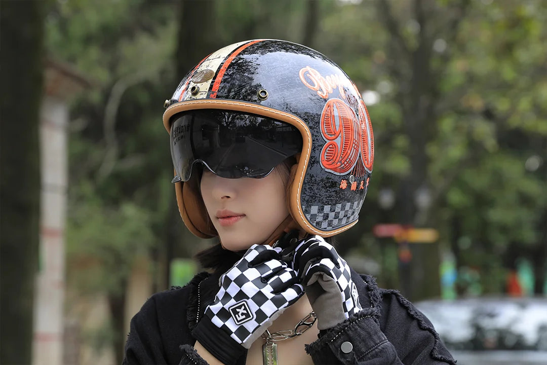 Rider in a black and orange open-face helmet holding a checkered glove