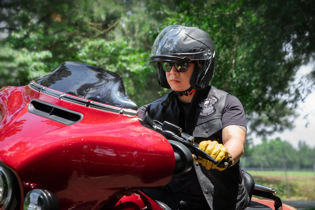 Rider in a helmet with the visor raised on a red touring motorcycle