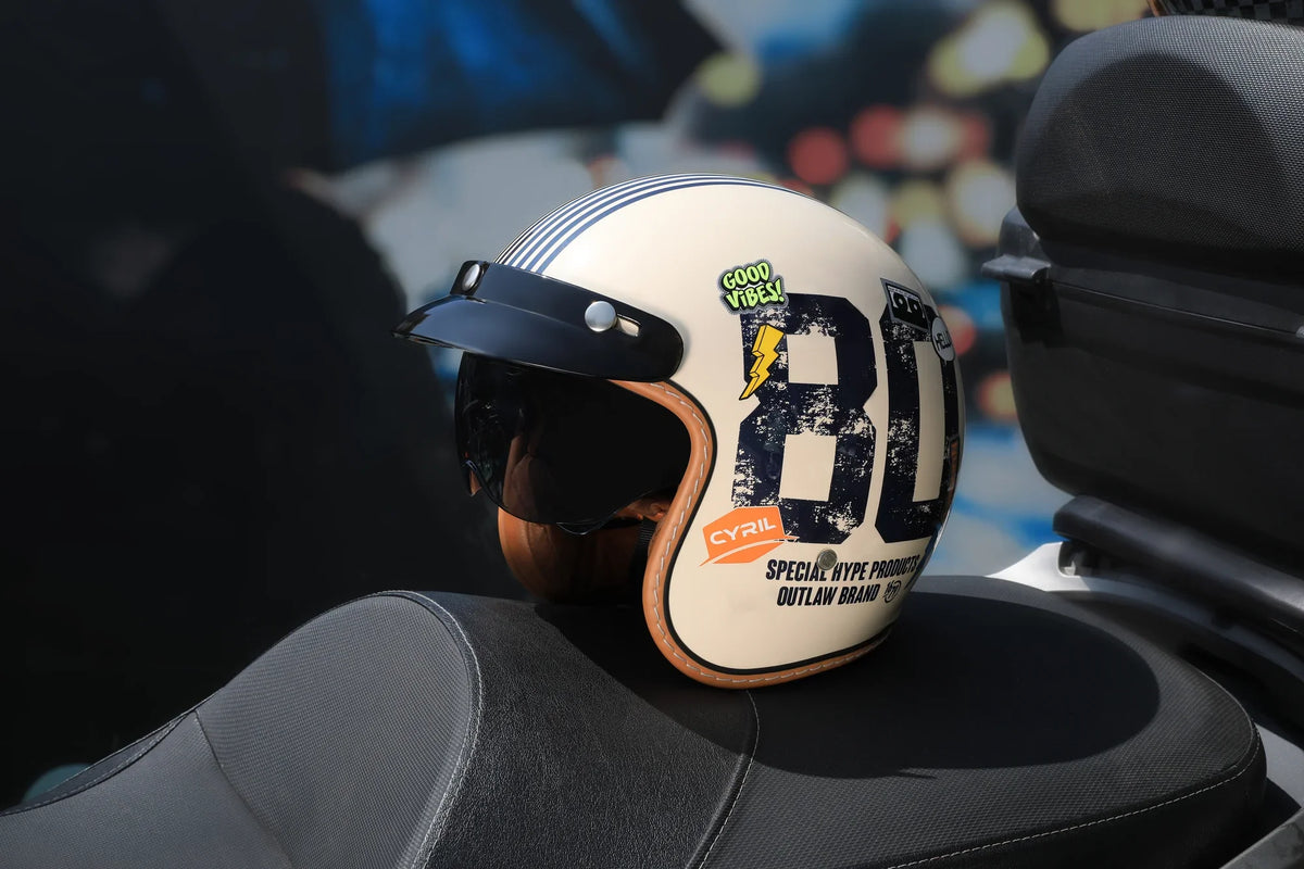 Cream open-face helmet with a number 80 graphic on a motorcycle seat