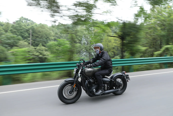 Rider in a dark full-face helmet on a cruiser along a guardrail